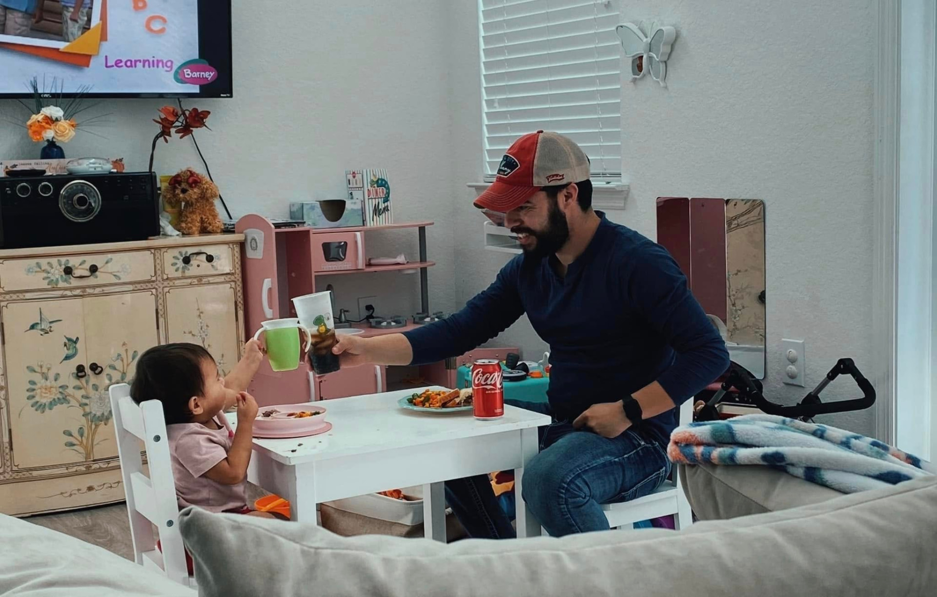 Elias sharing a meal with his daughter at a small table, toasting cups together